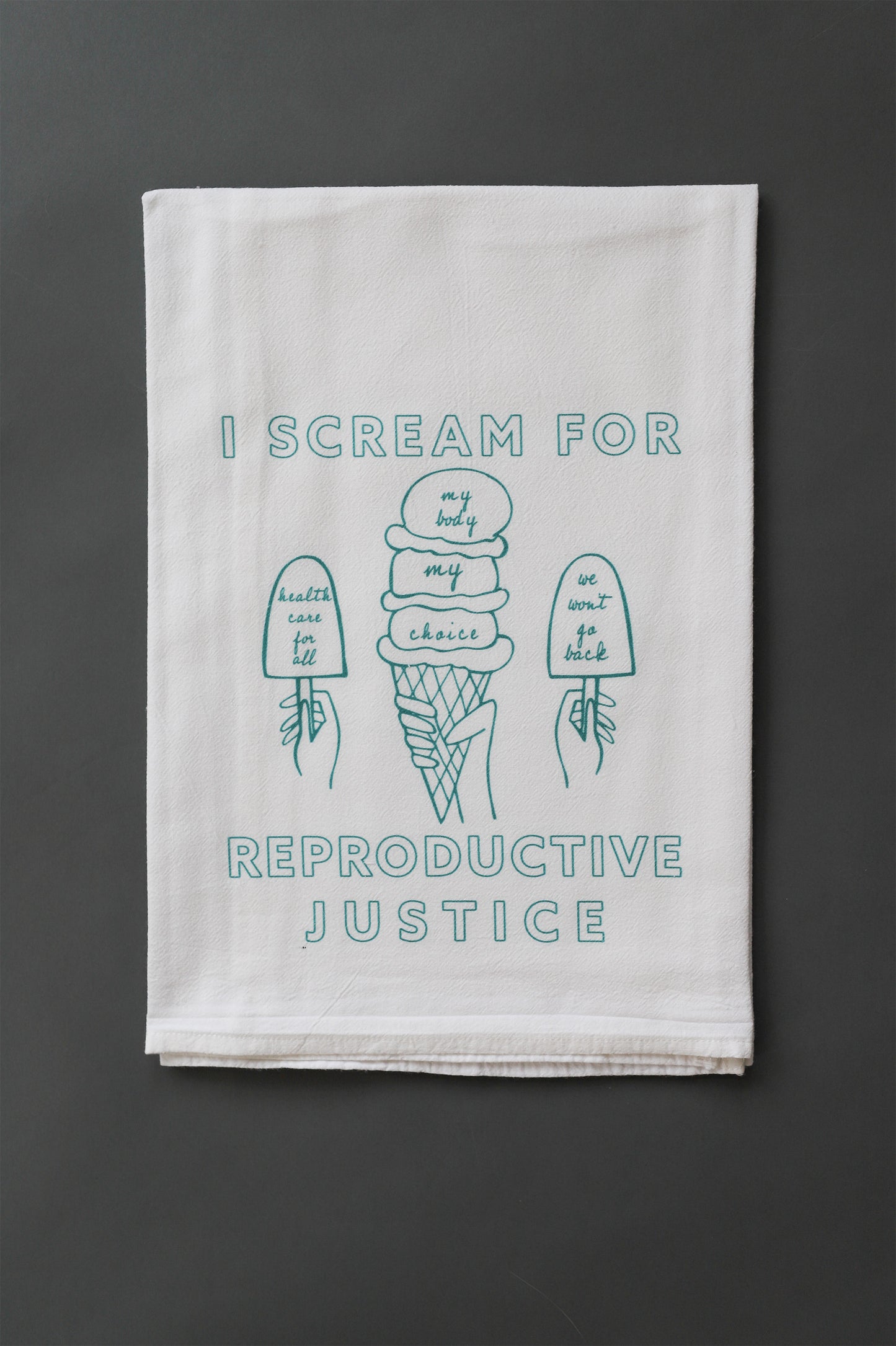 A white tea towel with the words I Scream for Reproductive Justice and ice cream designs in mint green