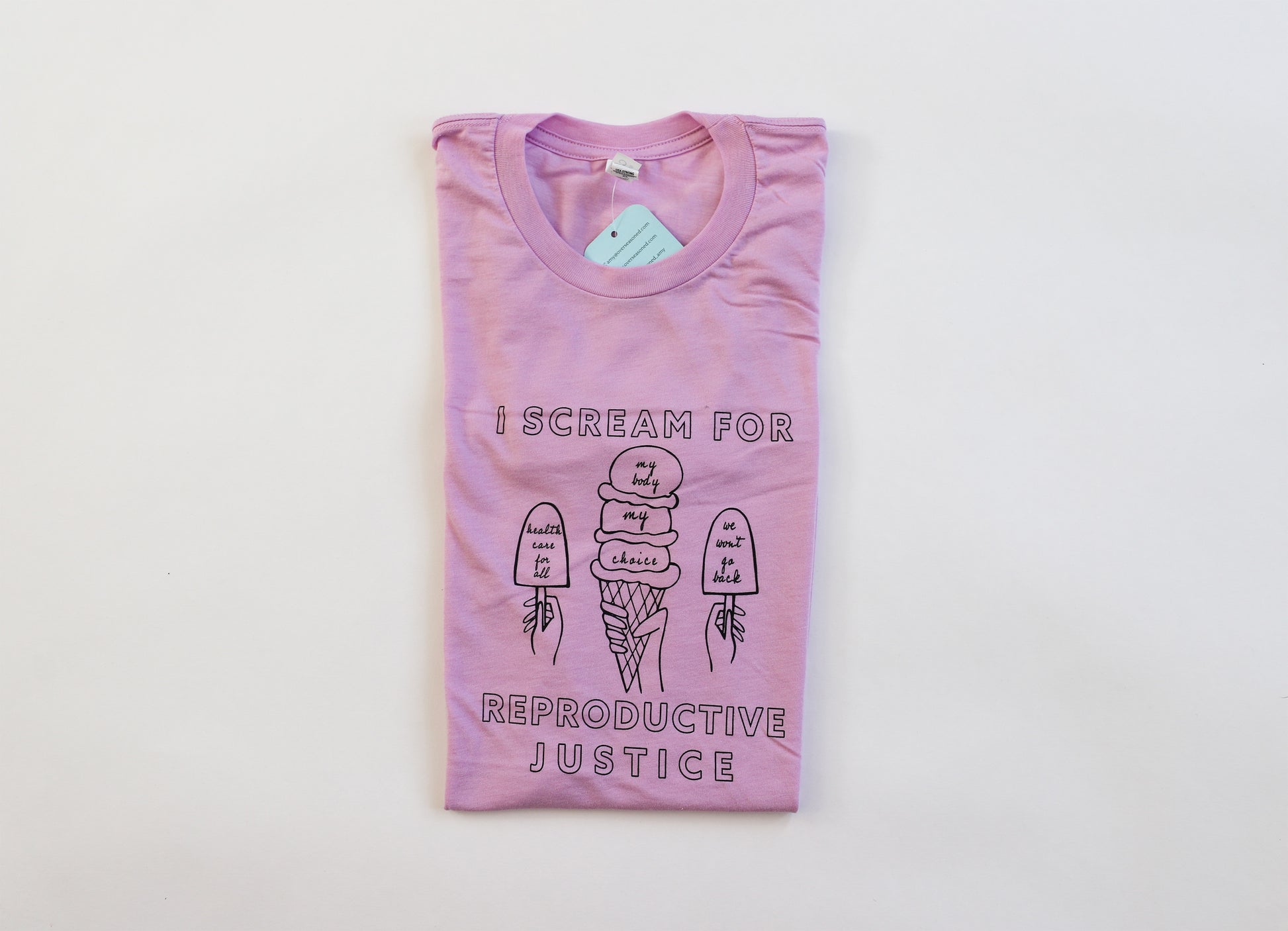 A folded lilac tee with "I Scream for Reproductive Justice" in black block letters and ice cream illustrations