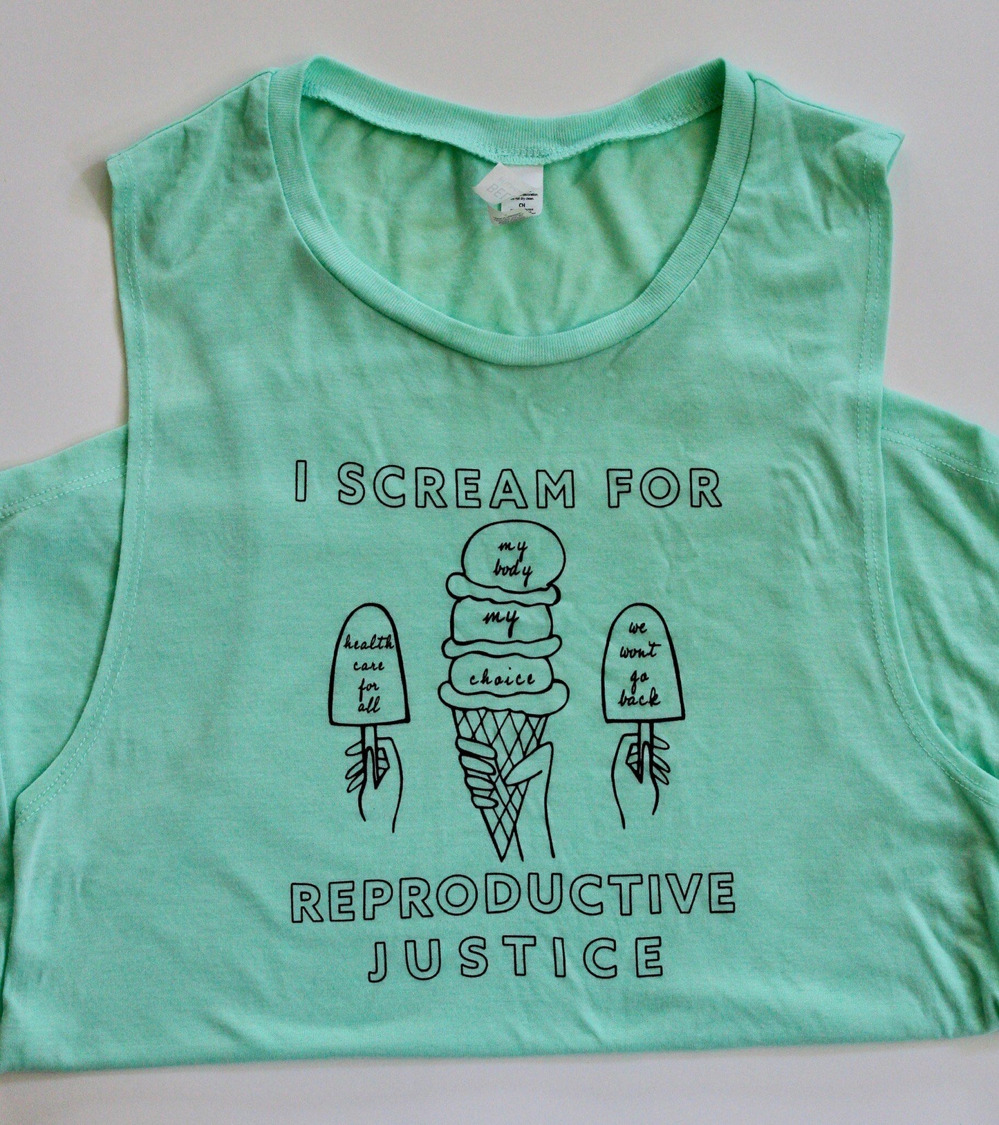 A mint green ladies tank with the words I Scream for Reproductive Justice in black block letters and ice cream themed illustrations