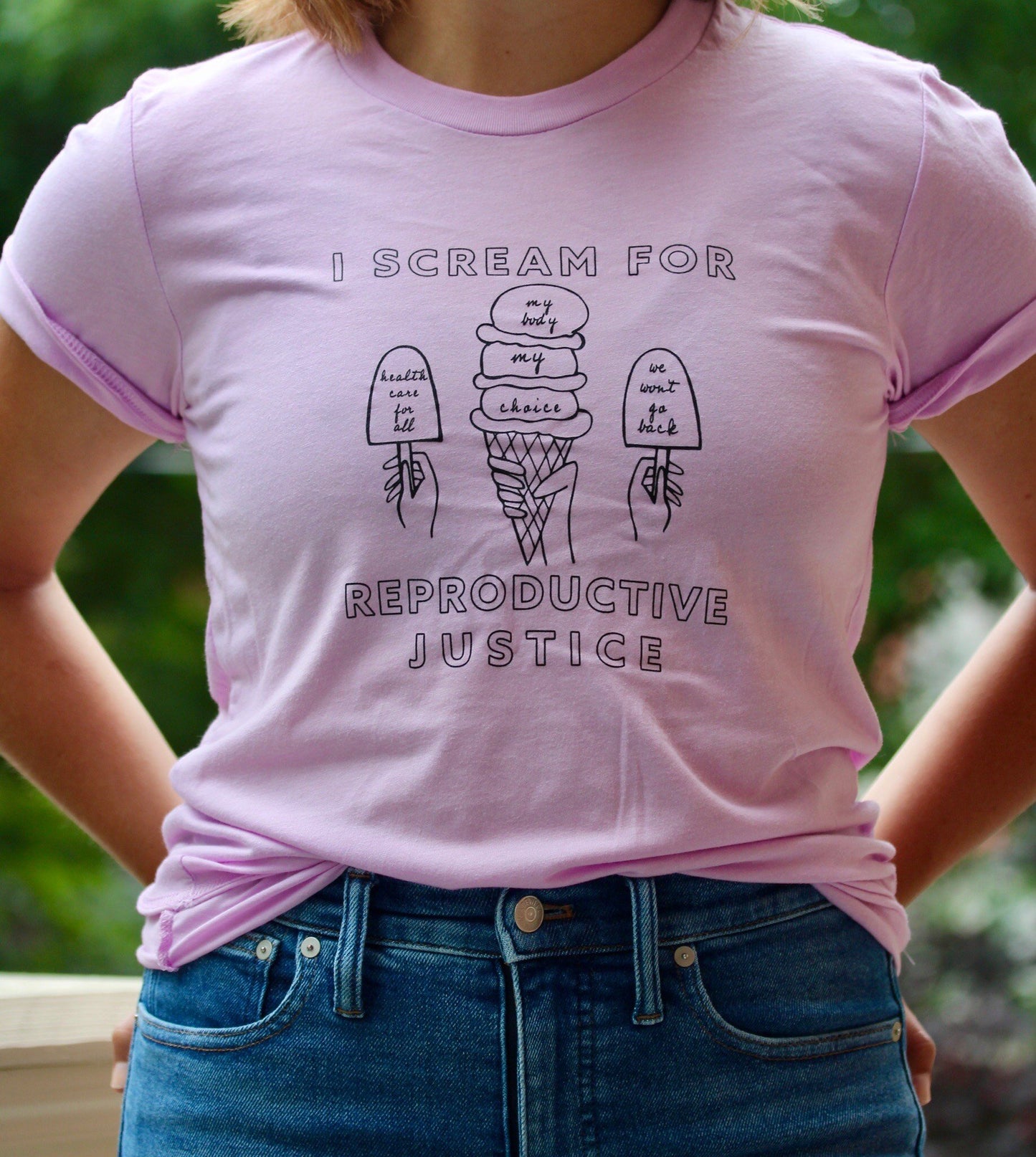 A woman wears a lilac "I Scream for Reproductive Justice" tee with jeans