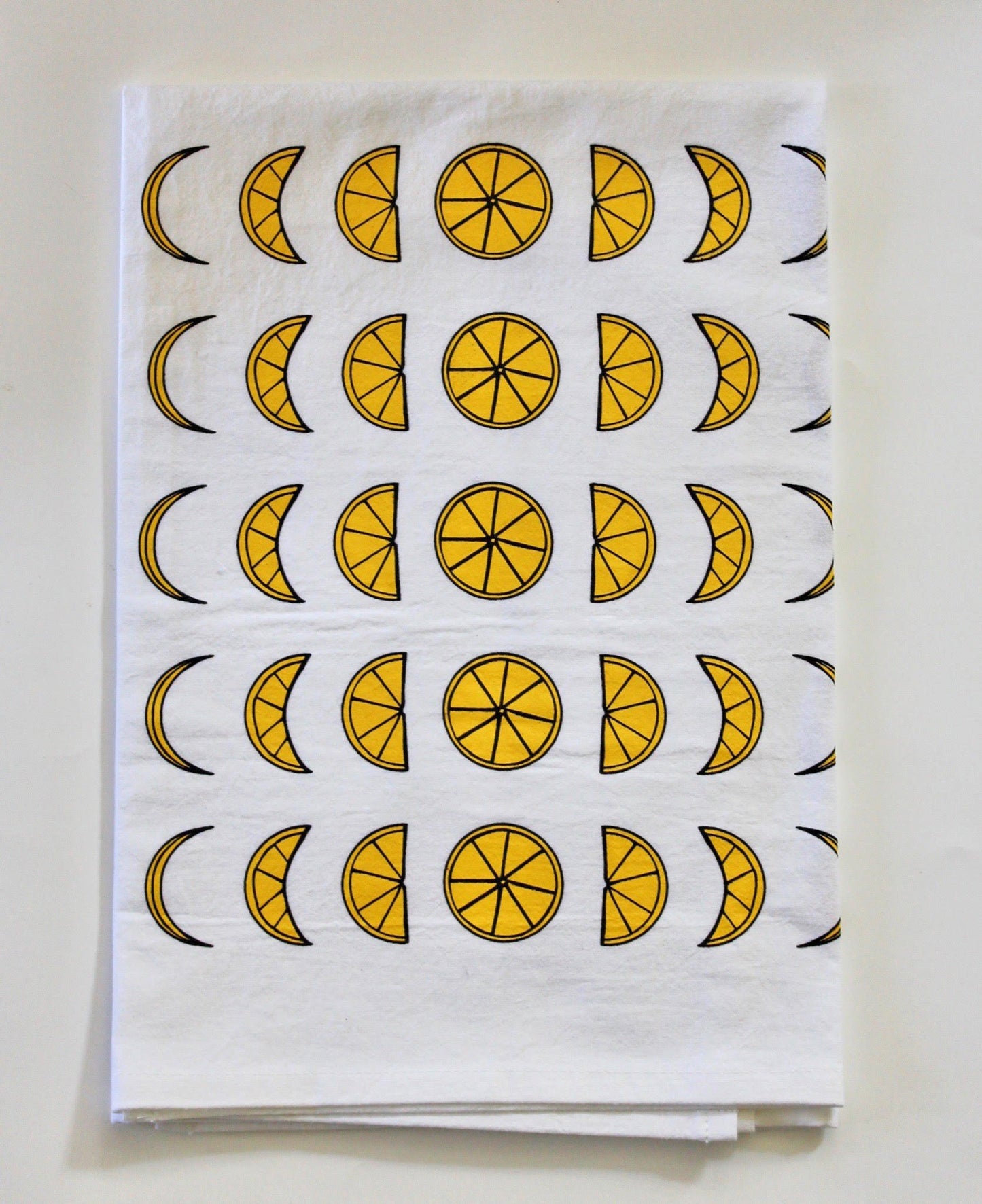 A white tea towel with a lemon moon phase design