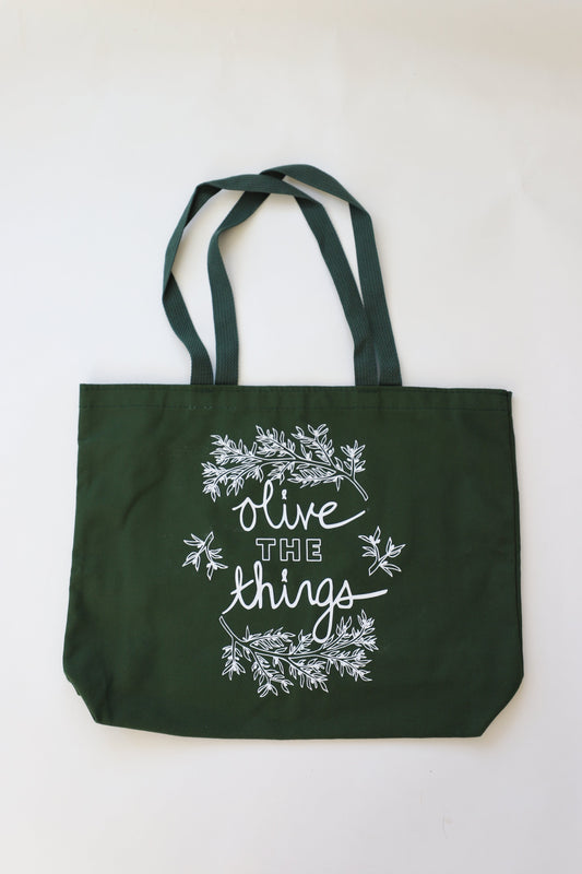An extra large dark green canvas tote with white writing that says "Olive the things"