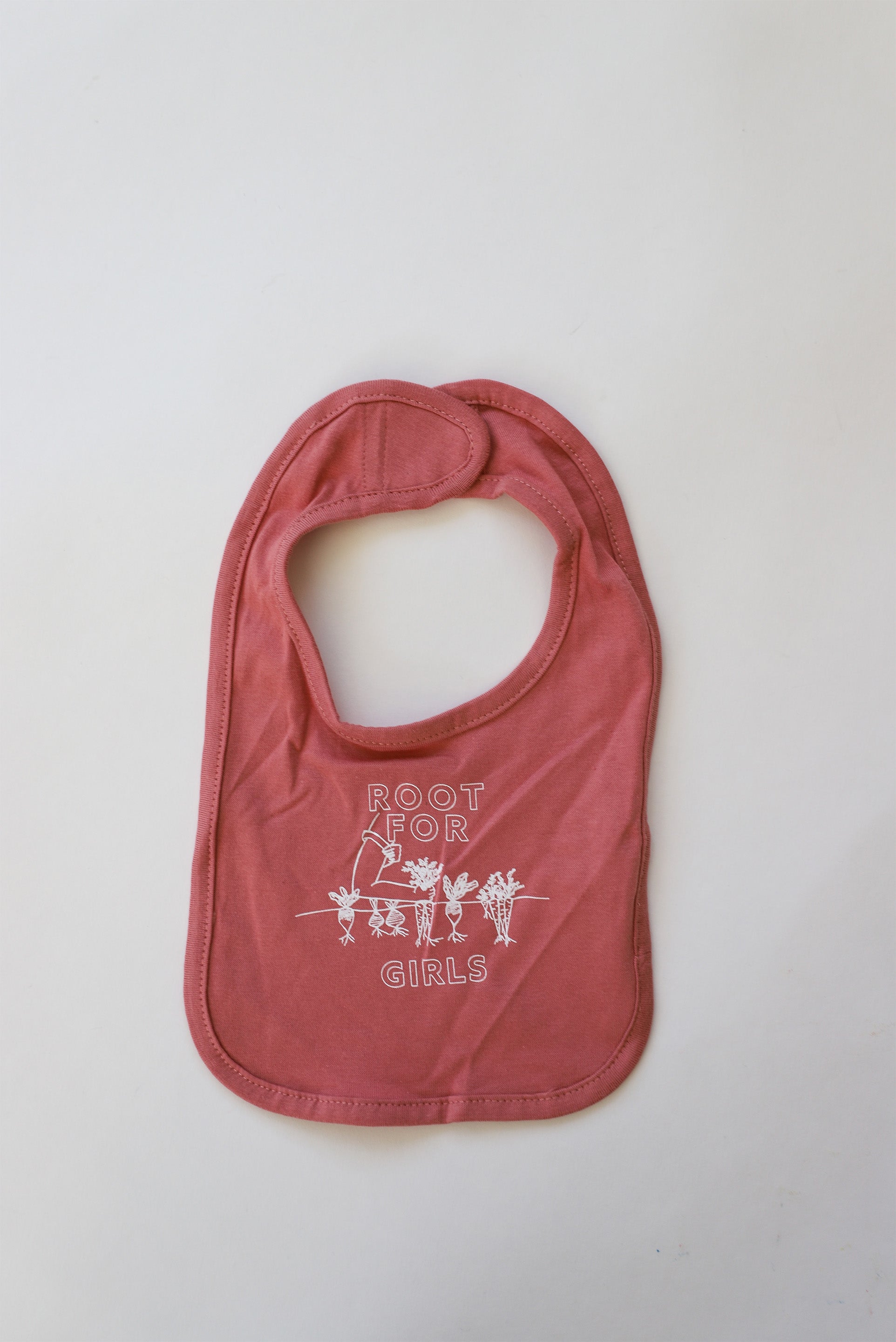 Pink baby bib with the words "Root for Girls" in white block letters with a gardening design