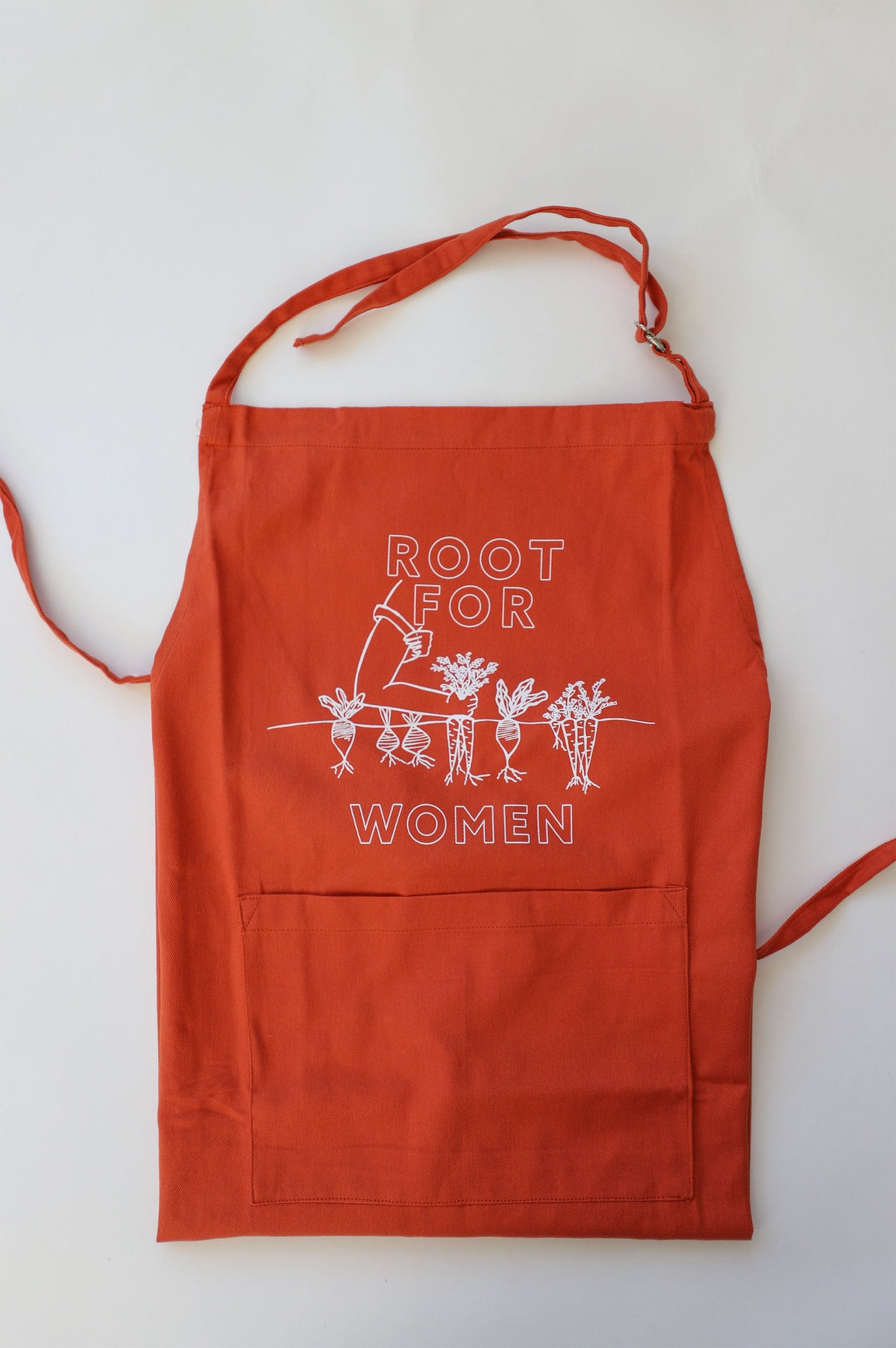 A folded carrot orange apron with "Root for Women" in block letters