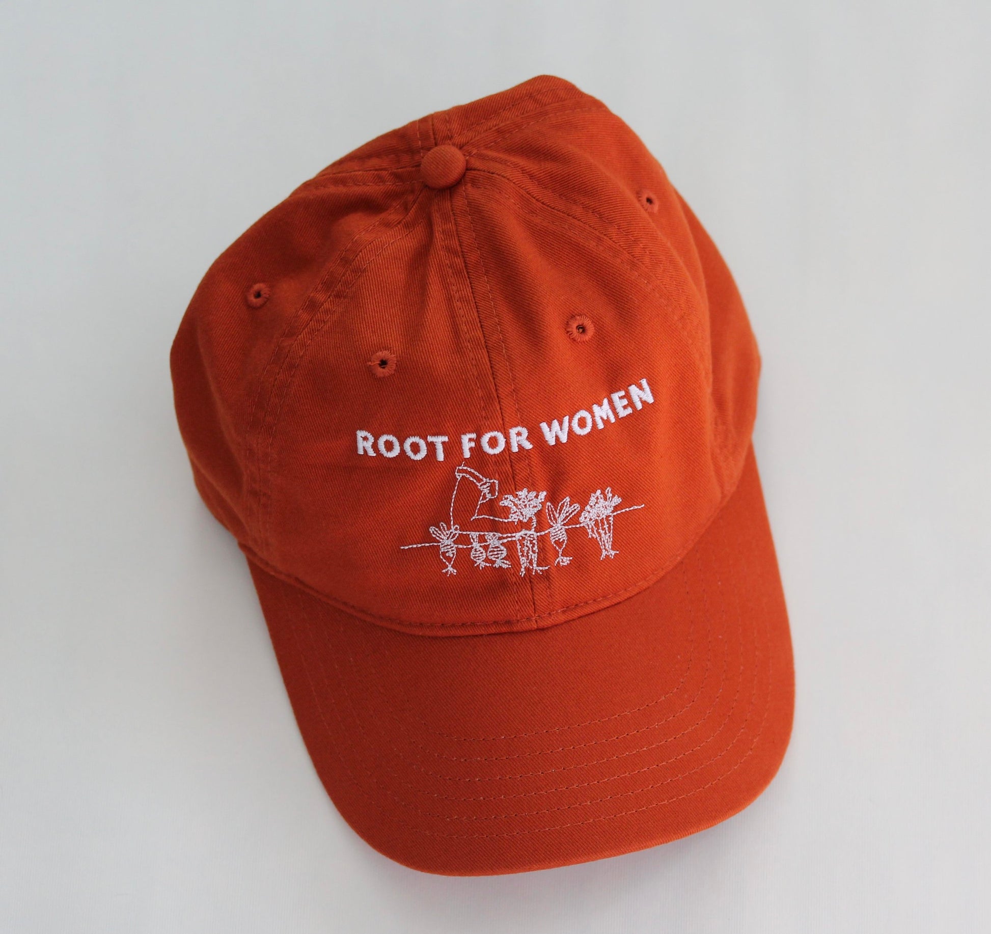 An orange hat reads "Root for Women" in white embroidery
