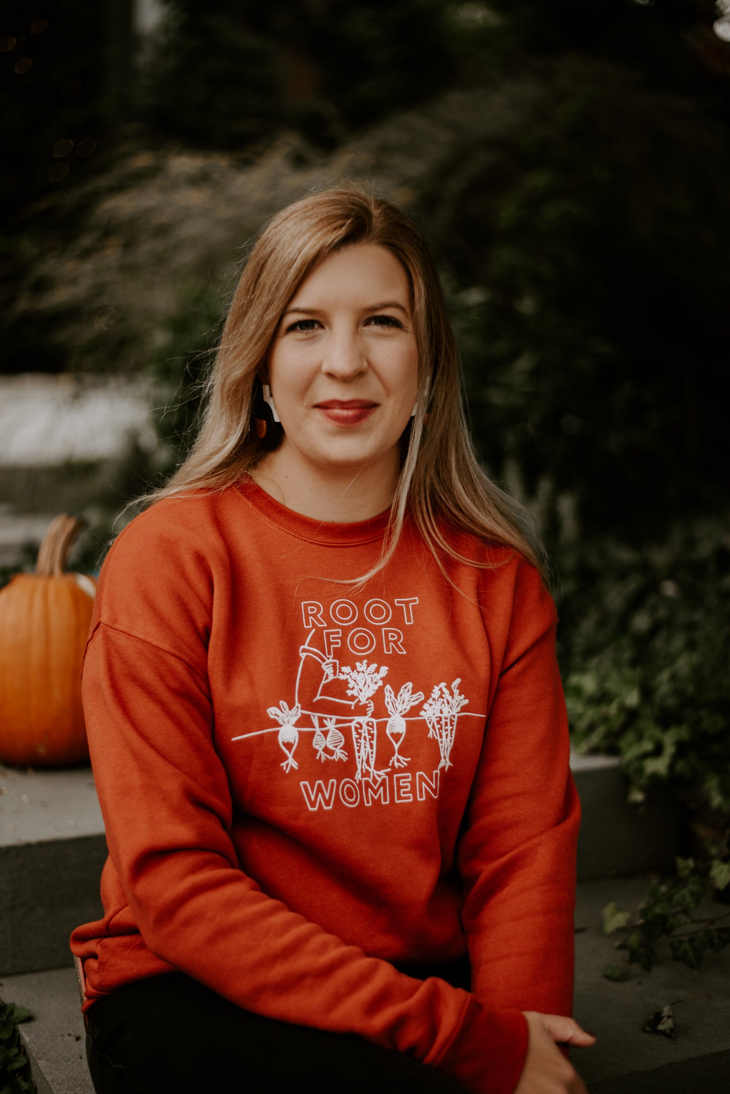 A woman wears a red "Root for Women" crewneck sweatshirt