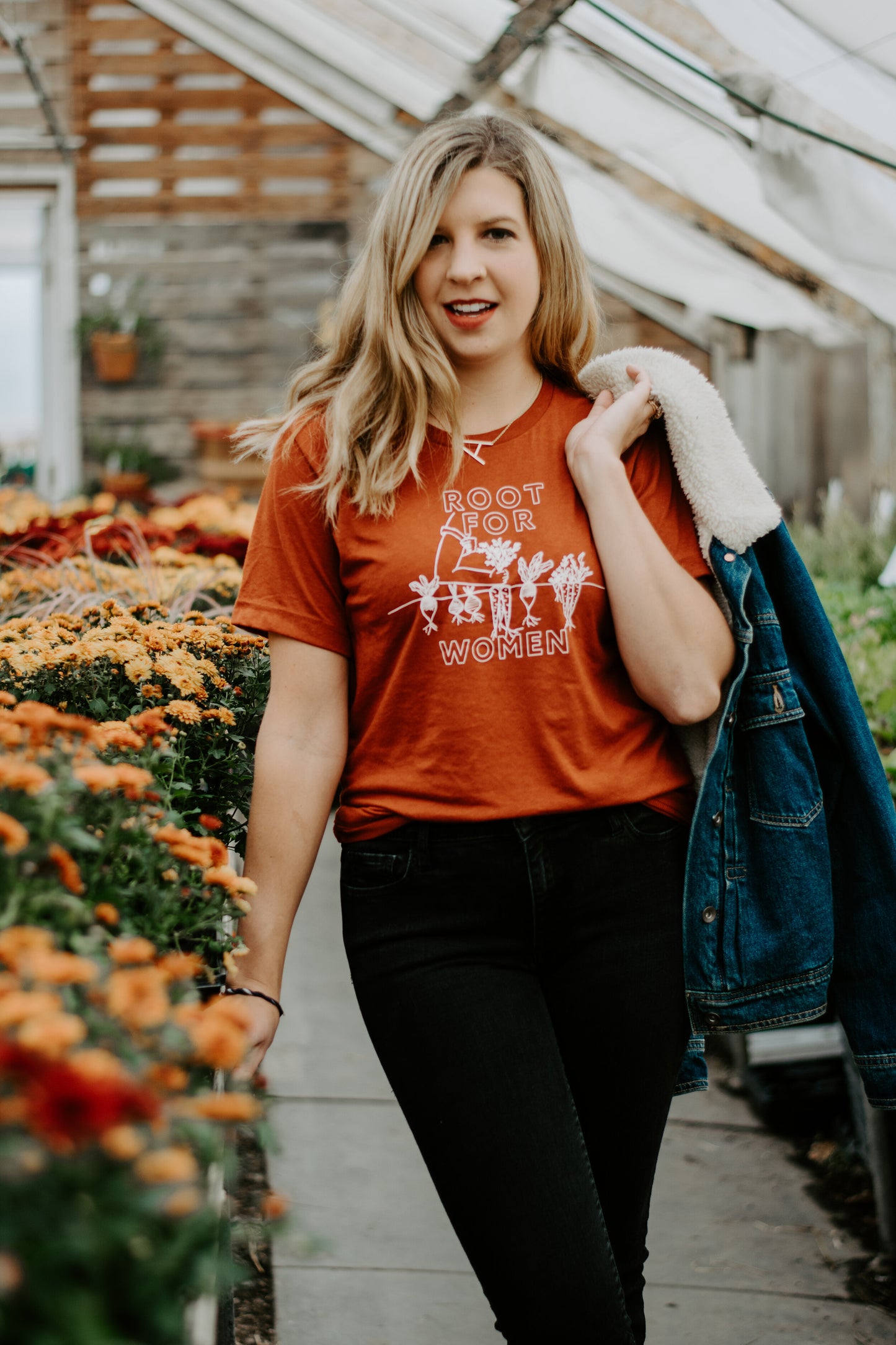 A woman wears a Root for Women t-shirt in a garden shop