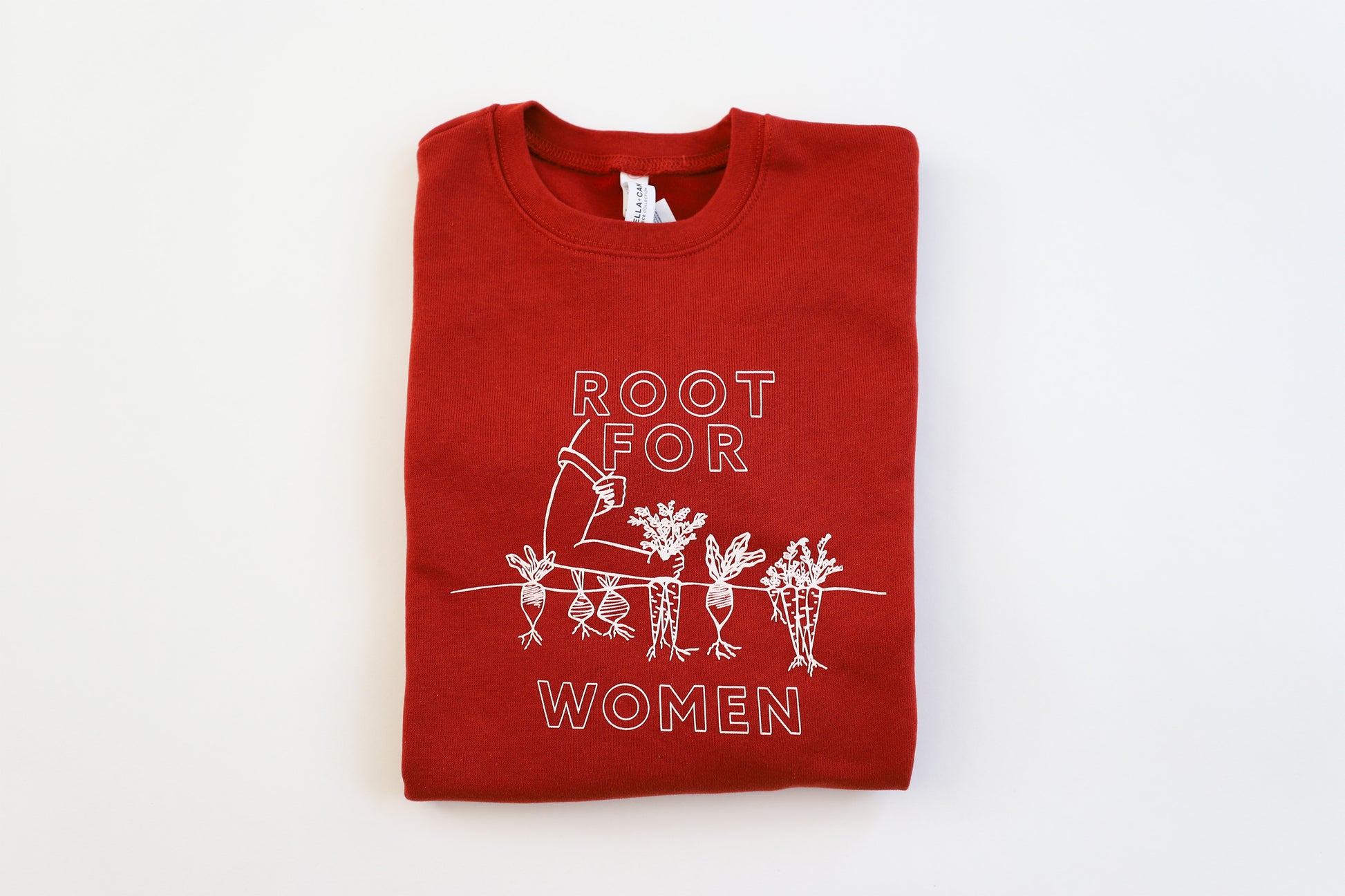 A folded red crewneck reads "Root for Women" in white block letters