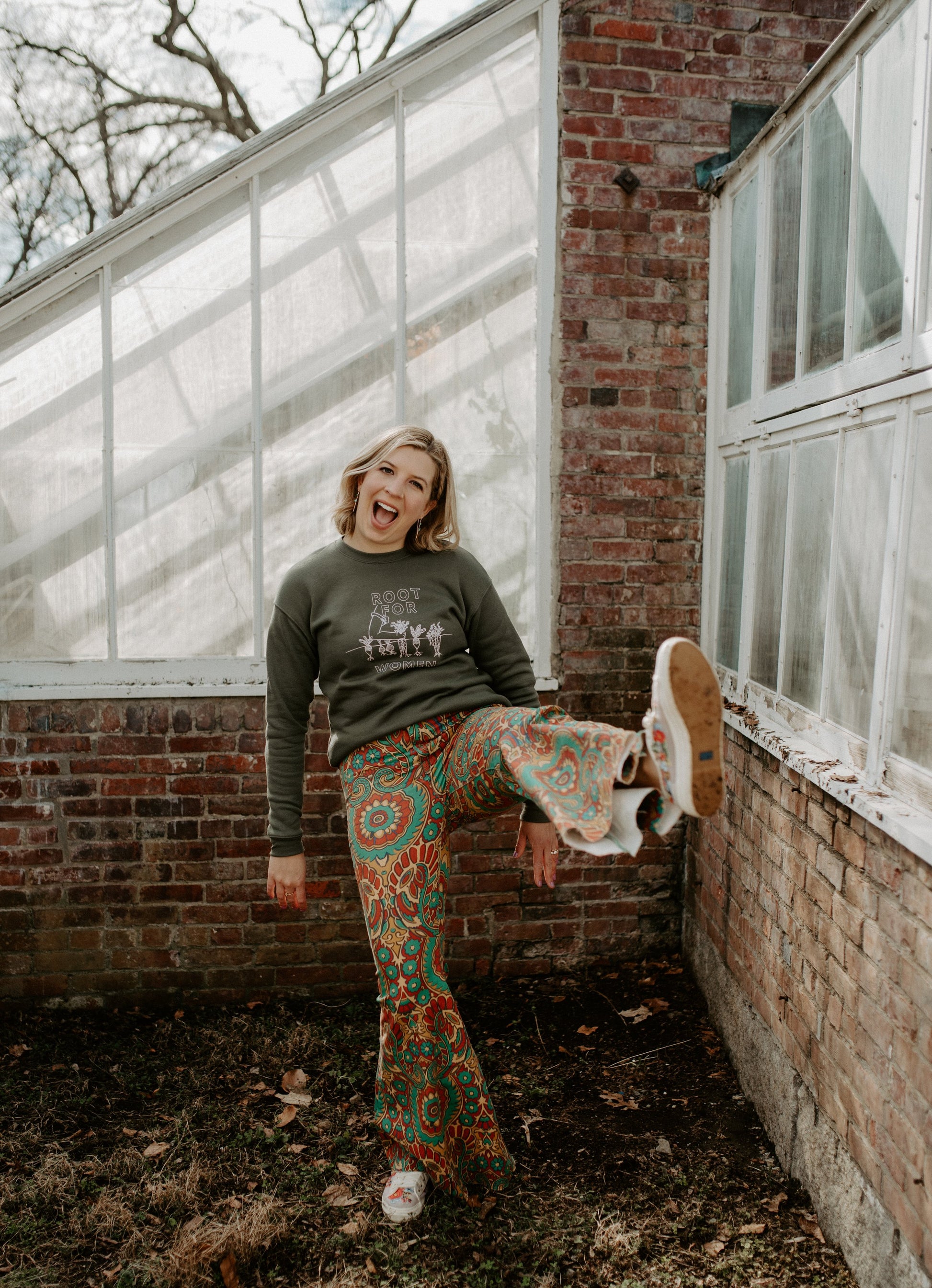 A woman wears a green "Root for Women" with paisley bellbottoms 