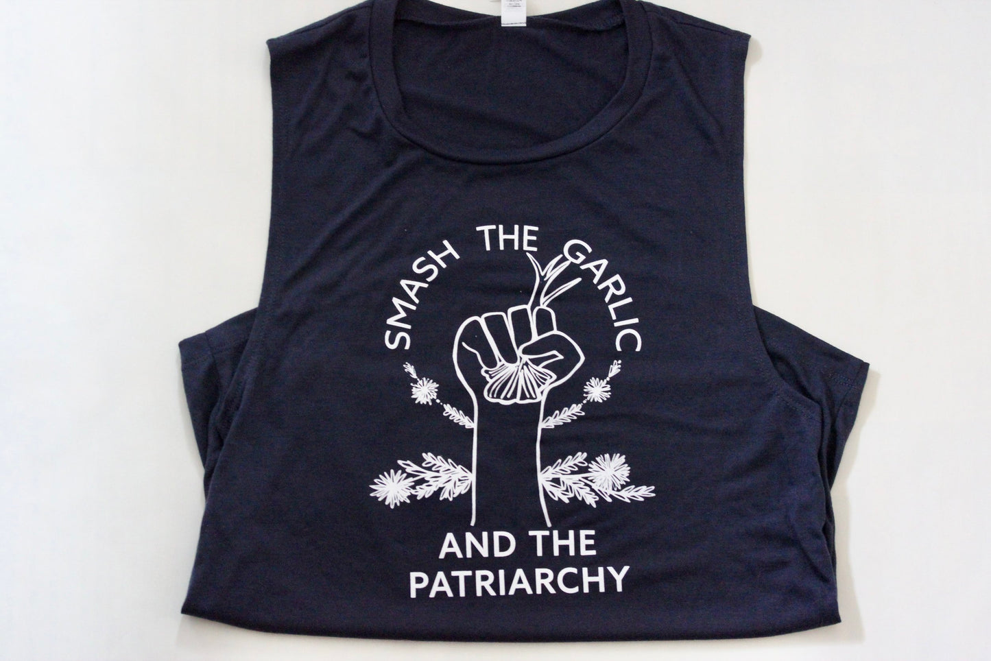 A navy blue tank with "Smash the Garlic and the Patriarchy" in white letters and an illustration of a hand holding garlic