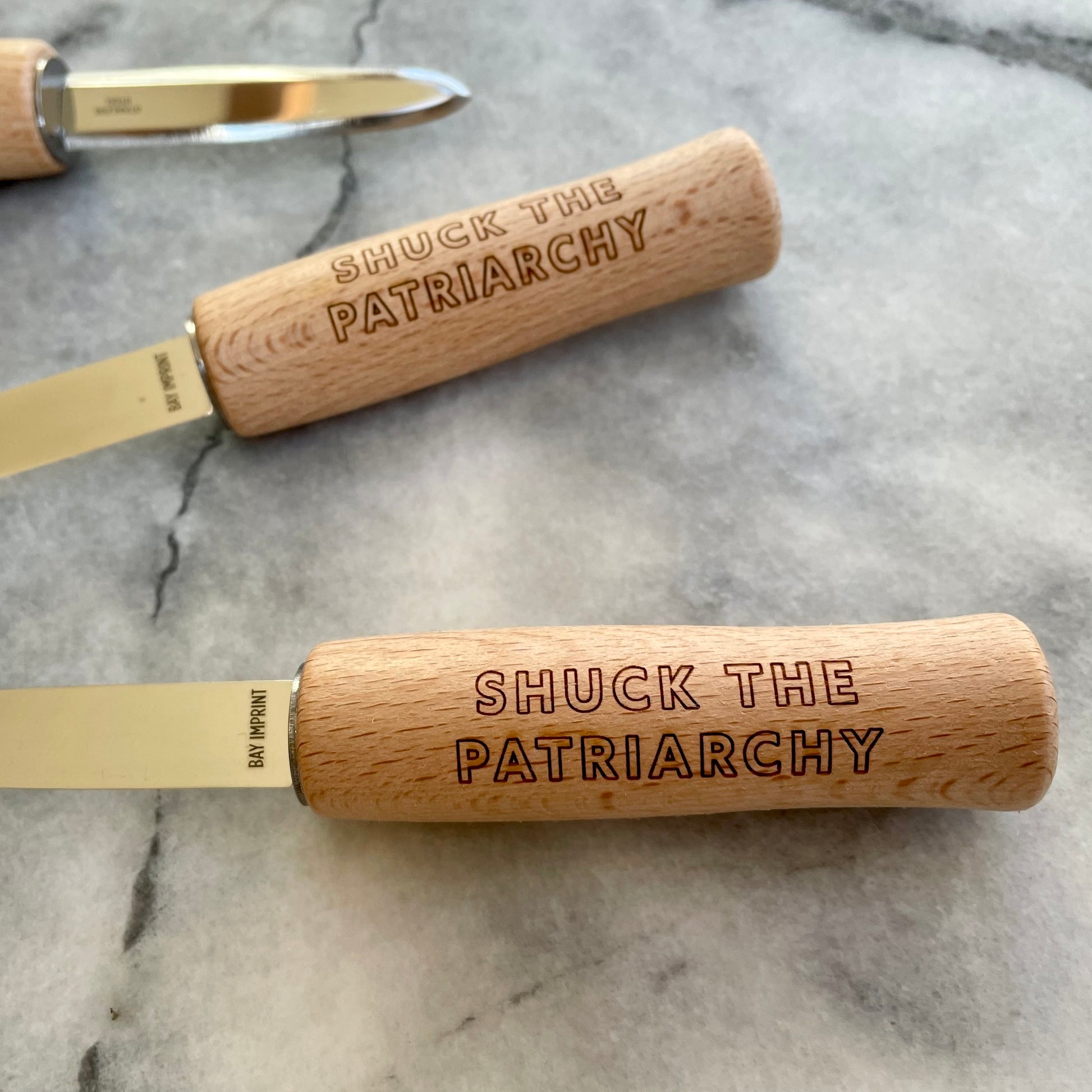 The handle of an oyster shucking knife reads "Shuck the Patriarchy"