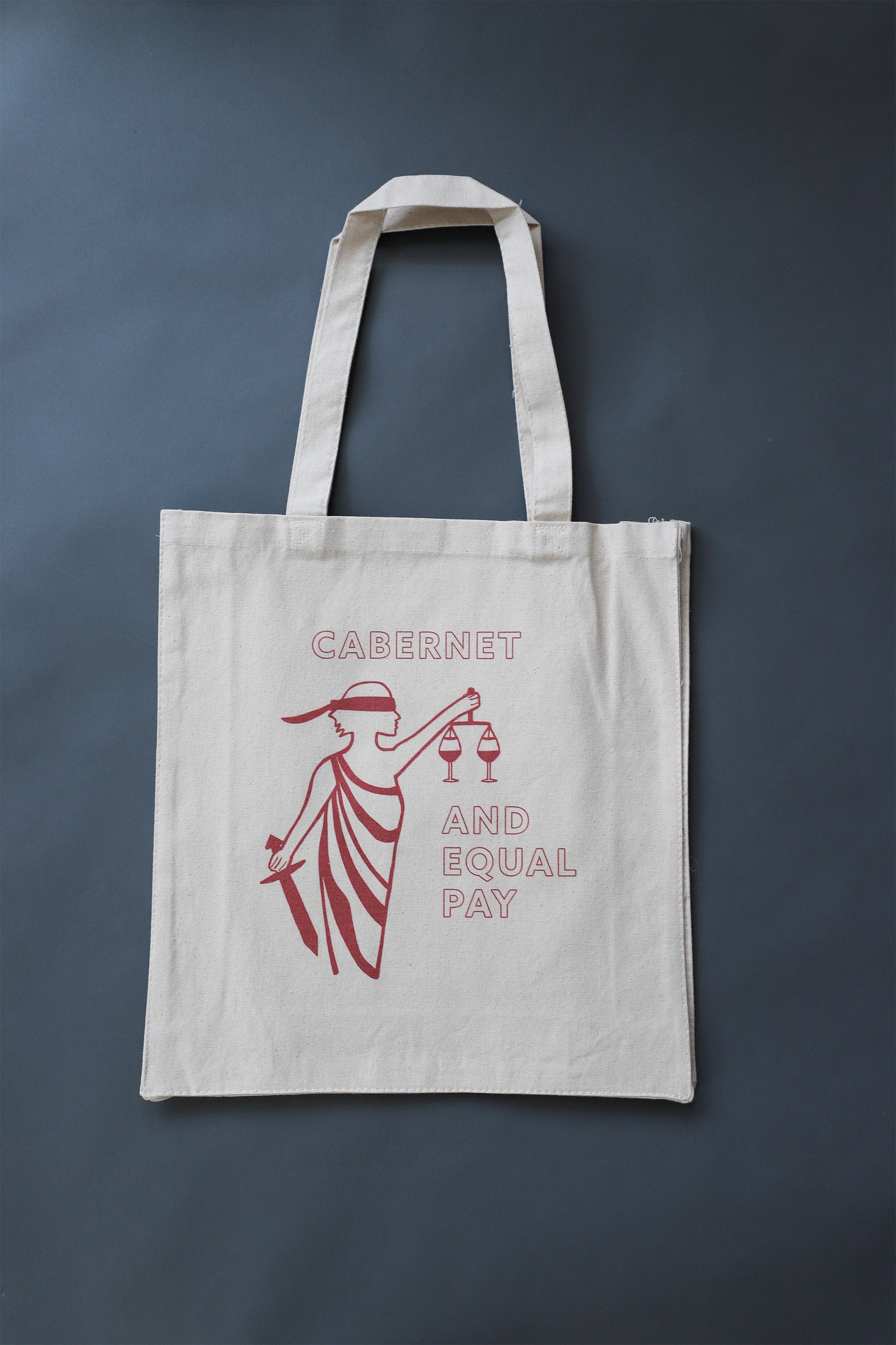 Sturdy canvas tote with red image of a women blindfolded holding 2 glasses of wine