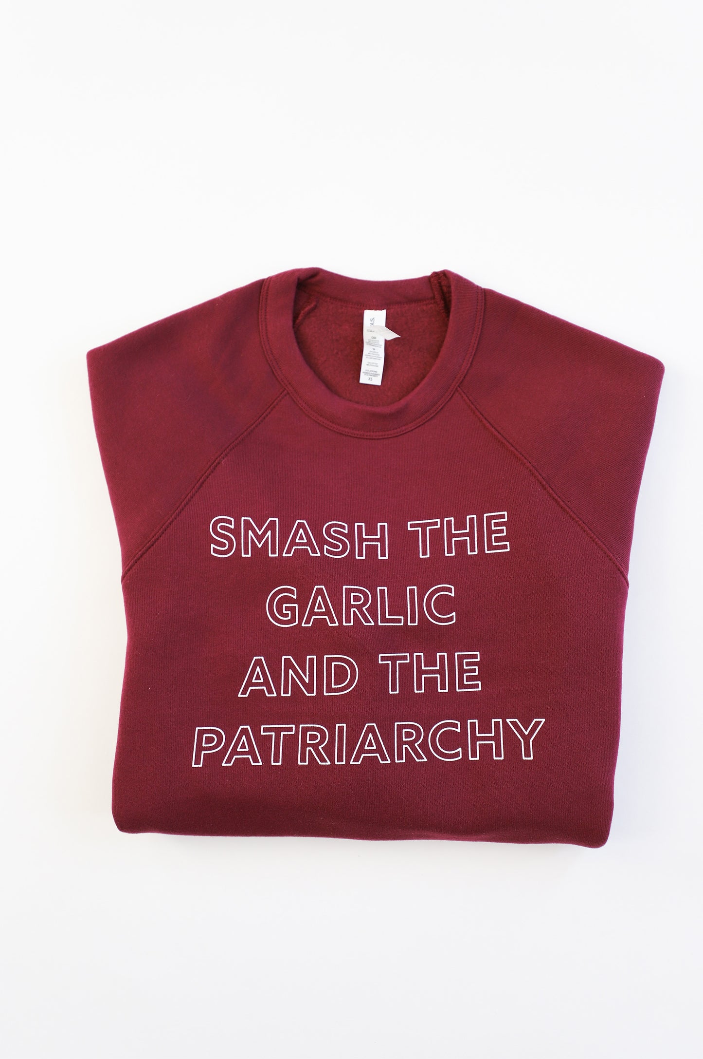 A maroon crewneck reads "Smash the Garlic and the Patriarchy" in white block letters