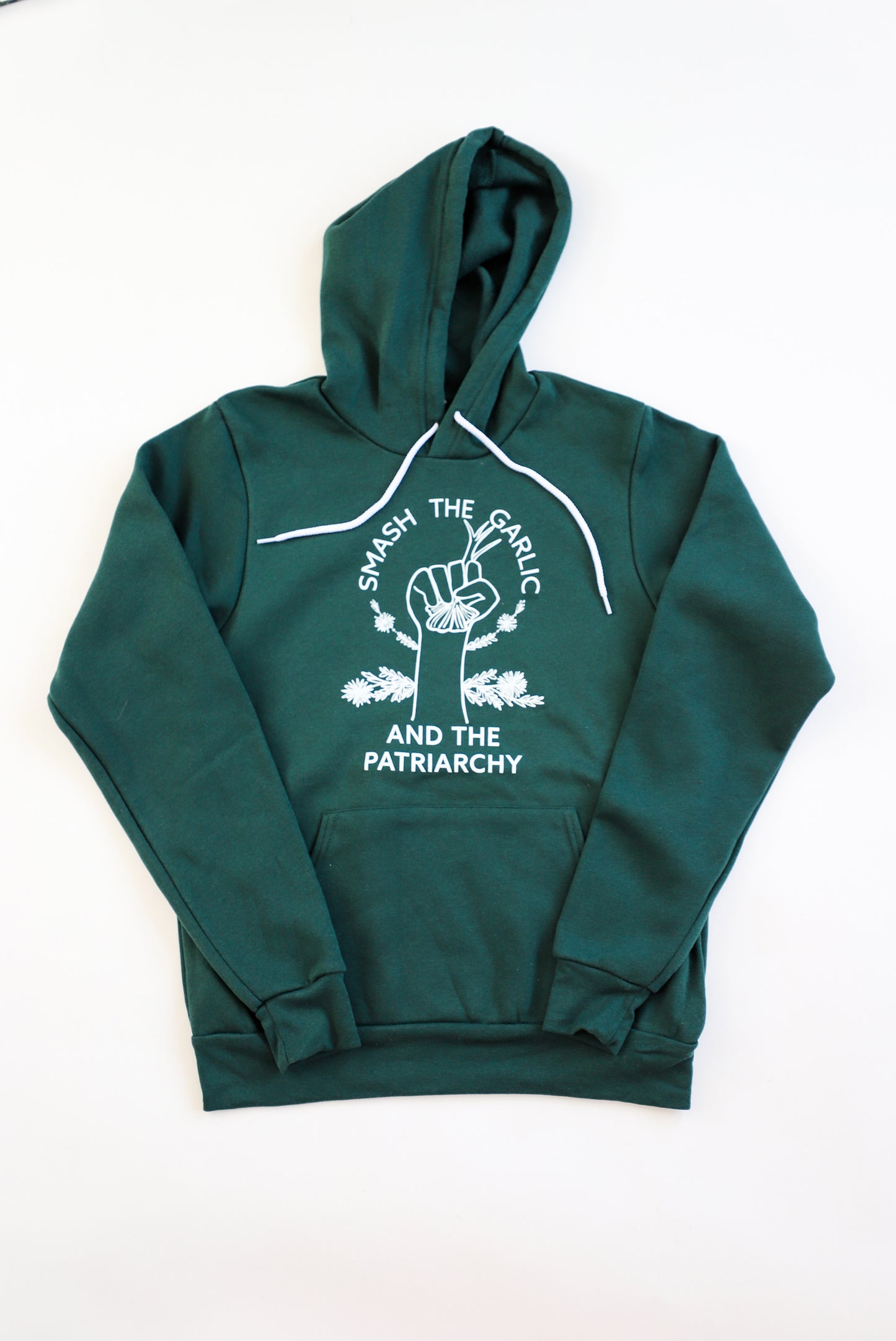 A dark green hoodie with the words "Smash the Garlic and the Patriarchy" and an illustration of a hand holding garlic