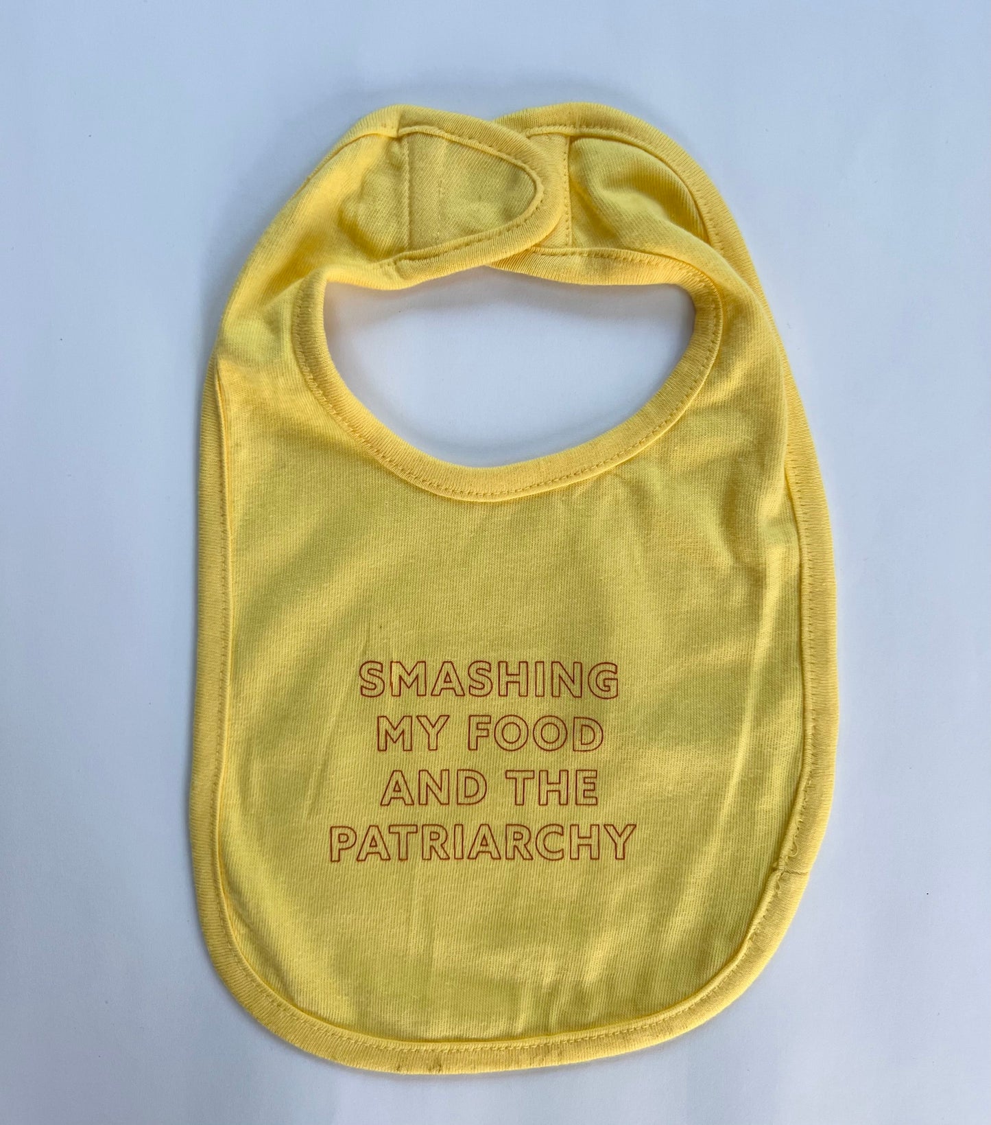 A yellow bib reads "Smashing my Food and the Patriarchy" in red block letters